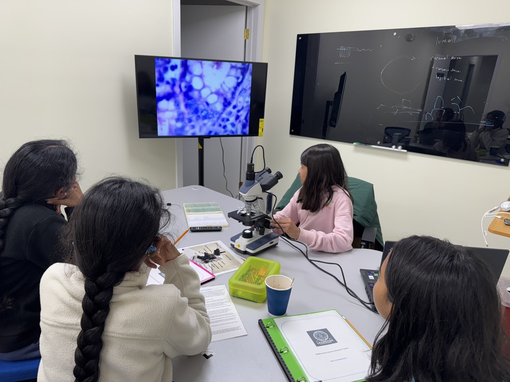 Students using a microscope during a Lexington Science Academy class